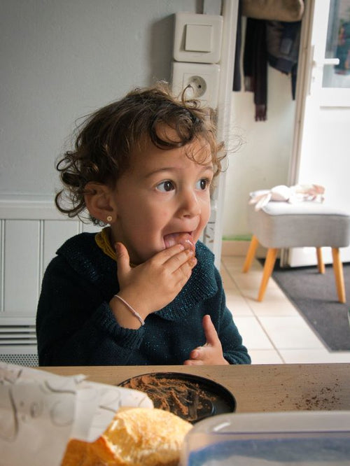 petite fille entrain de lécher ses doigts dans une cuisine