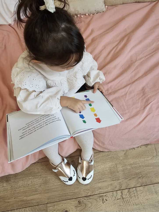 petite fille avec un livre et des chaussons en cuir souple de chez taz marque bordelaise